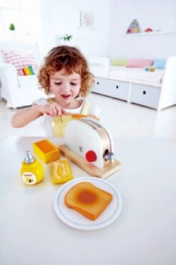 Hape Toaster 7-teilig | Spielküchen-Zubehör -Holzspielzeug-Peitz E3148 Pop up Toaster Set with child 2
